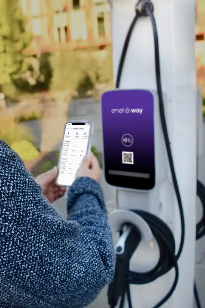 women using enel x charing app on phone to control charge of her EV