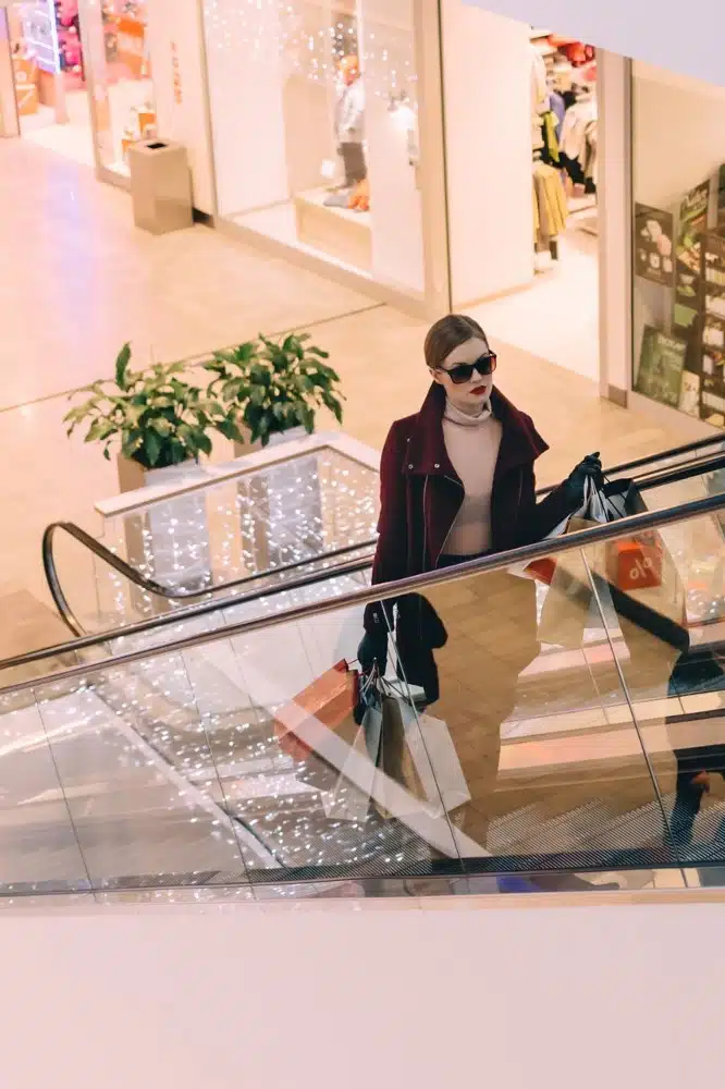 women going up escalator in shopping mall
